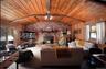 Living area featuring wooden walls, wood ceiling, a ceiling fan, carpet flooring, and a wood stove