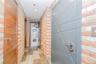 Laundry area featuring brick wall and stacked washing machine and dryer