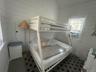 Bedroom with wooden walls, lofted ceiling, and cooling unit