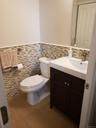 Half bath with tile walls, a wainscoted wall, vanity, and tile patterned floors