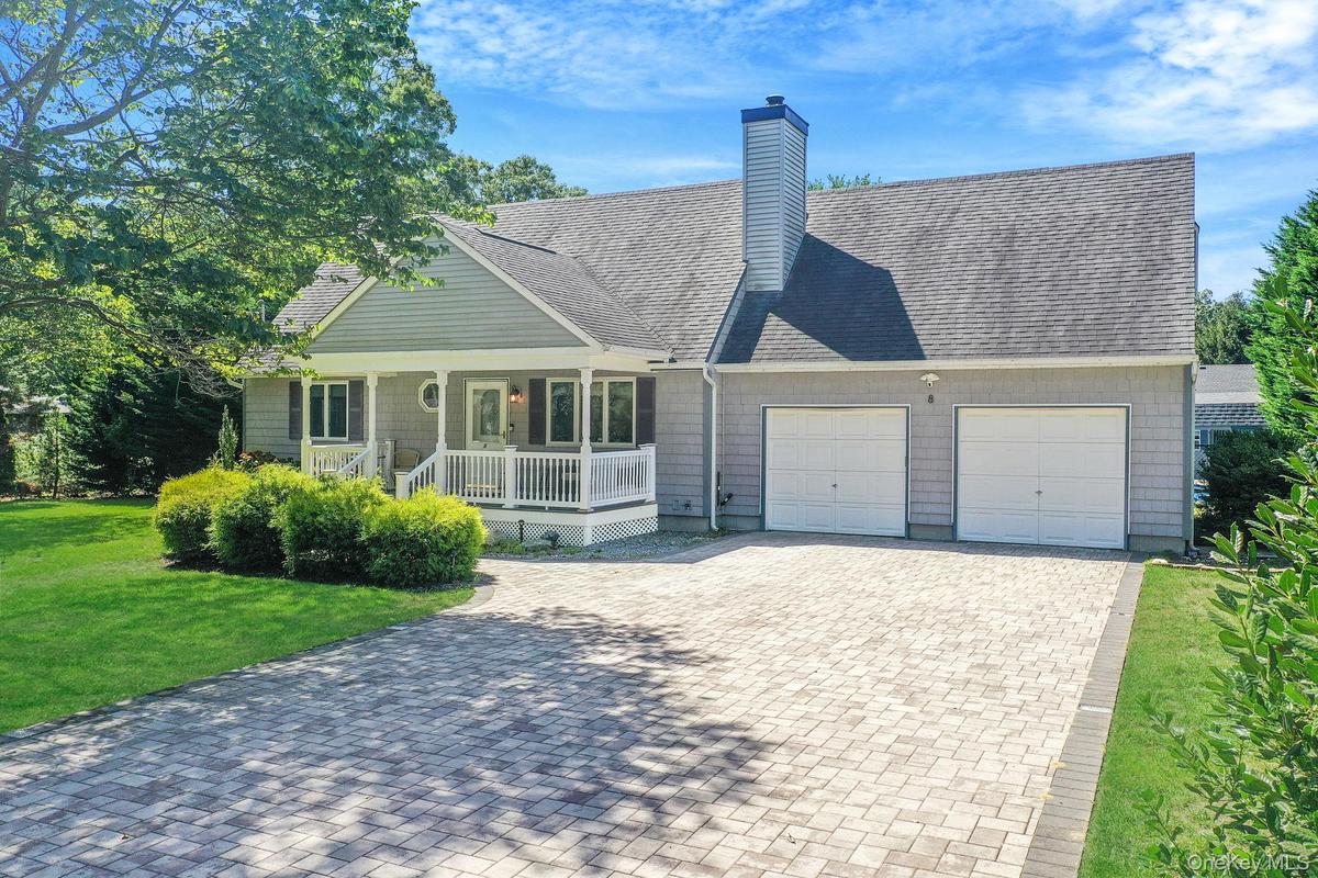 View of front of property featuring a porch, a shingled roof, decorative driveway, and a front lawn