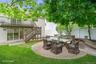 Expansive backyard featuring a circular paver patio, stone-faced raised planters, and a manicured lawn