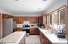 Kitchen featuring stainless steel appliances, brown cabinetry, light countertops, light tile patterned floors, and recessed lighting