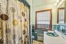Bathroom with radiator, vanity, a shower with shower curtain, tile walls, and wainscoting
