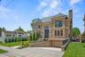 View of front of home featuring a high end roof, brick siding, concrete driveway, an attached garage, and a chimney