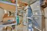 Basement mechanical room featuring exposed ductwork, water heater, and utility shelving