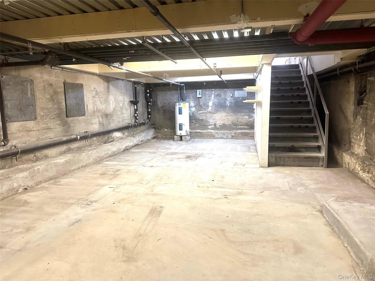 Unfinished basement featuring stairs and water heater