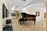 A refined art corridor where the grand piano becomes both centerpiece and statement, enhanced by a custom backlit stone installation that elevates the