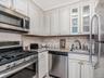 Kitchen featuring stainless steel appliances, light stone counters, and white cabinetry