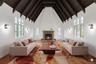 The breathtaking living room is the heart of the home, featuring soaring cathedral ceilings, dramatic exposed beams, oversized windows, and a stunning