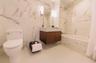 Bathroom with a combined bath / shower with marble appearance, toilet, vanity, and stone wall
