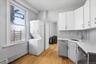 1st Floor Apartment kitchen/laundry room features light wood flooring, white upper cabinetry, and grey lower cabinetry