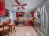 Kitchen with dark brown cabinets, stainless steel appliances, light stone countertops, ornamental molding, and backsplash