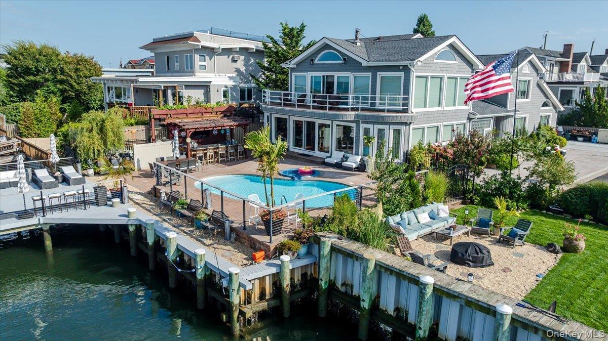 Back of property featuring a patio, an outdoor living space with a fire pit, a water view, and a pergola
