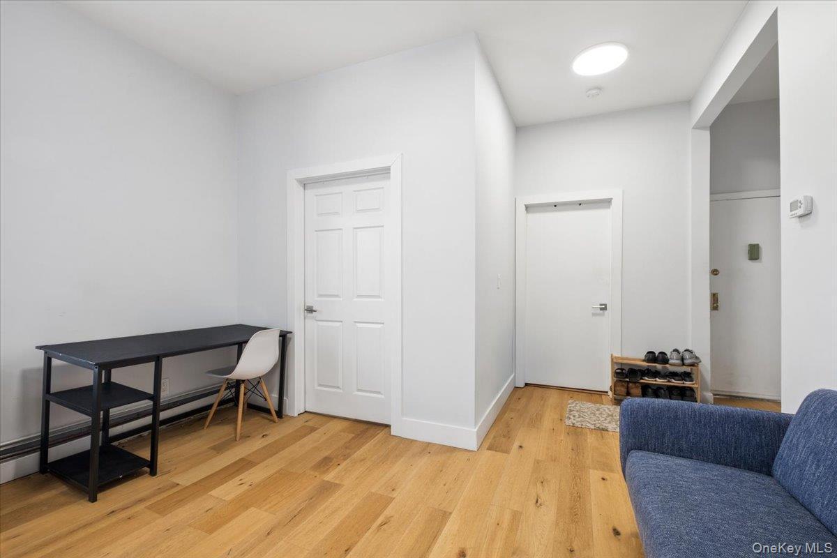 1st Floor Apartment entry into living room and doors to 2 bedrooms; features light hardwood floors and white walls, offering a bright and versatile en