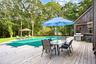Wooden deck with a covered pool, outdoor dining area, a grill, and view of wooded area