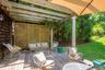 Spacious outdoor deck featuring natural wood flooring, a slatted pergola, a decorative privacy screen, a column support, and an attached umbrella for