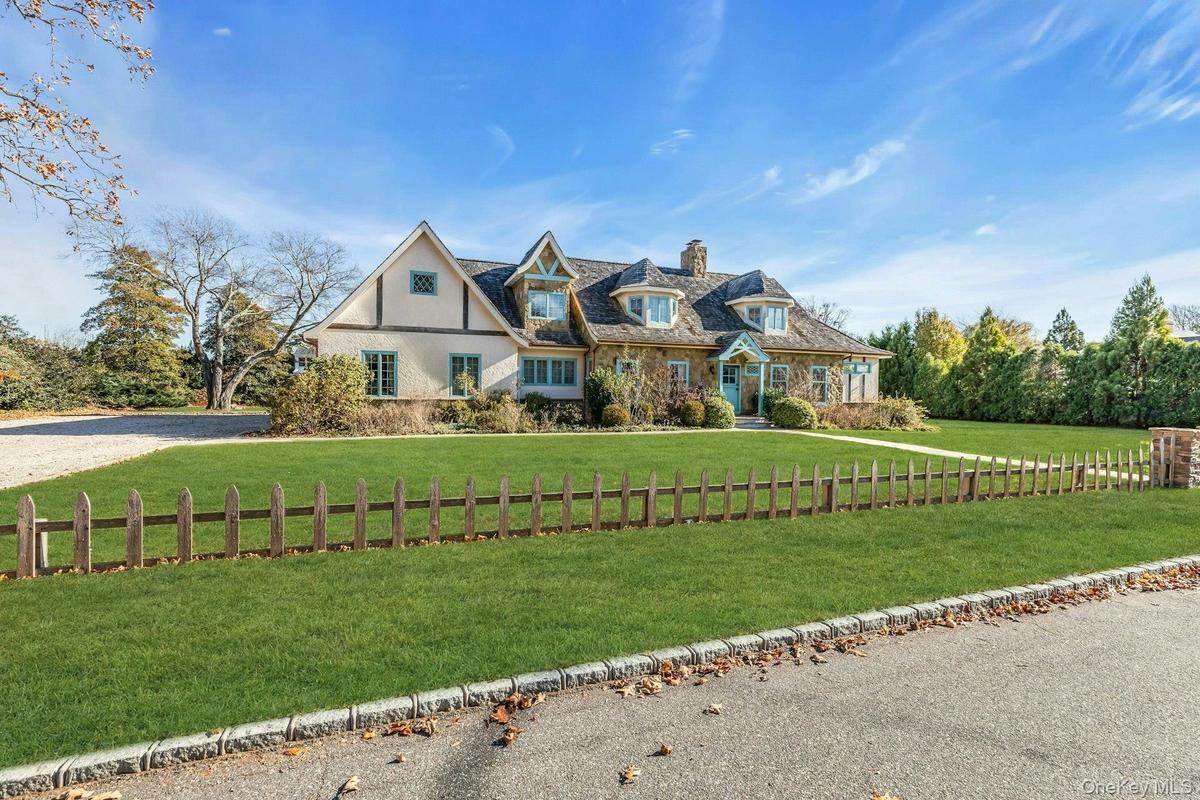 View of front of house featuring stone siding, a chimney, and a front lawn