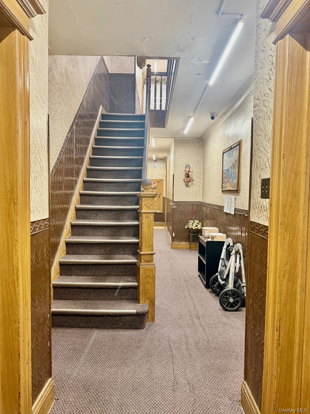 Stairs featuring a wainscoted wall, wallpapered walls, carpet, and wooden walls