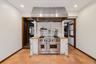Kitchen with white cabinets, double oven range, ventilation hood, and stacked washing machine and dryer