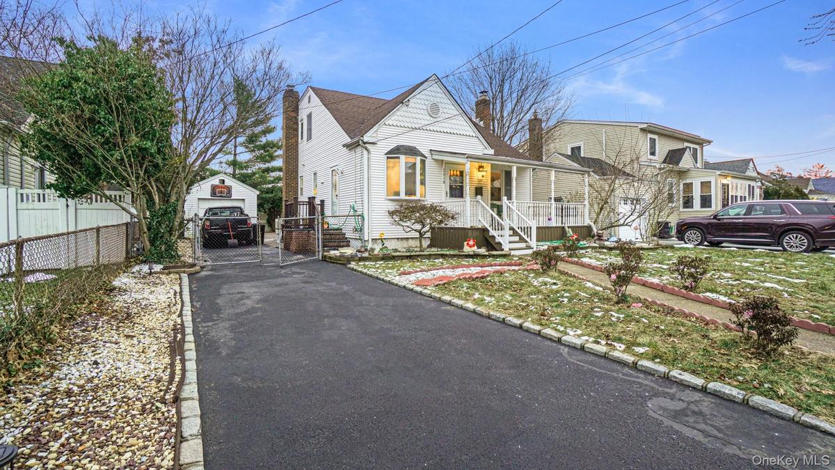 View of front of home with a gate, a chimney, driveway, covered porch, and fence