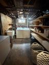 Utility area featuring a laundry sink, window, and exposed ceiling joists.Apt. #1