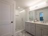 Bathroom featuring double vanity, a stall shower, and light marble finish flooring