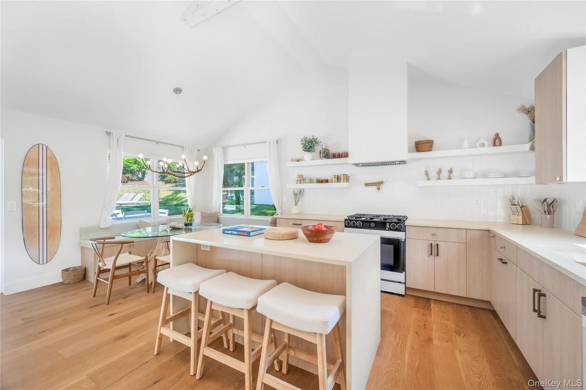 Kitchen featuring open shelves, a kitchen bar, pendant lighting, range with gas stovetop, and decorative backsplash