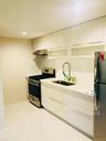 Kitchen featuring gas range, freestanding refrigerator, light marble finish flooring, modern cabinets, and wall chimney exhaust hood