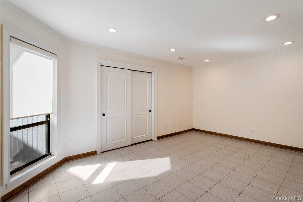 Room with light tile flooring, recessed lighting, and a window featuring a roller shade