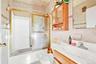 Full bath featuring tile walls, bath / shower combo with glass door, vanity, and decorative backsplash
