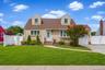 Dormered property with a stucco exterior, front entry with an arched gate, attached garage, and a concrete driveway