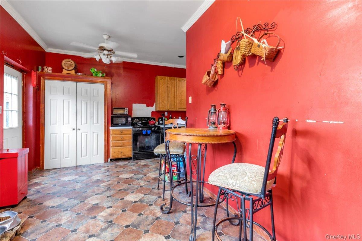 Kitchen with ceiling fan, black appliances, and ornamental molding