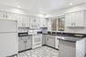 Kitchen with backsplash, white appliances, sink, dark stone countertops, and white cabinetry