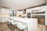 Kitchen with stainless steel appliances, wall chimney range hood, light wood-type flooring, light stone countertops, and recessed lighting