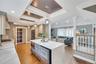 Spacious open-concept kitchen featuring light-toned cabinetry, a waterfall-edge island with an integrated microwave, quartz countertops, and recessed