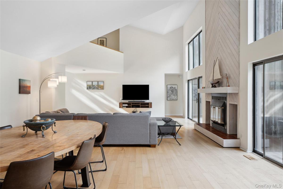 Living room featuring light wood-style flooring, a large fireplace, and a high ceiling