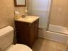 Full bathroom with tile walls, vanity, shower / bath combination with glass door, and dark speckled floor
