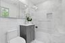 The beautifully renovated primary bath showcases timeless marble finishes, a sleek glass-enclosed tub and shower, and elegant contemporary fixtures, c