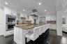 Kitchen featuring ornamental molding, white cabinets, dark stone counters, a breakfast bar area, and glass insert cabinets