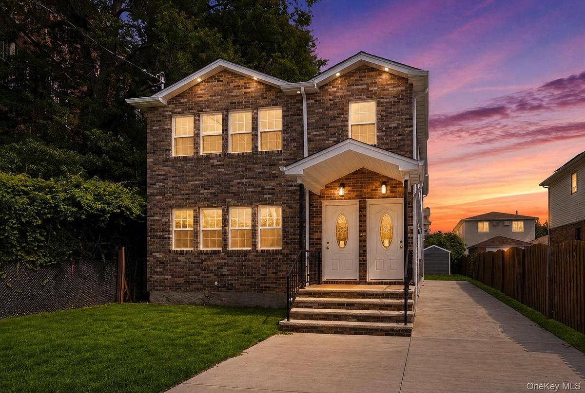 Brick exterior with white trim, dual entry doors, covered front porches with recessed lighting, concrete driveway, and manicured lawn