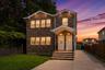 Brick exterior with white trim, dual entry doors, covered front porches with recessed lighting, concrete driveway, and manicured lawn