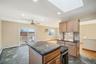 Kitchen featuring recessed lighting, dark stone counters, a skylight, wine cooler, and a center island