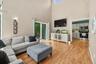 Open-concept living space featuring vaulted ceilings, abundant natural light from sliding glass doors, and wood-finish flooring throughout
