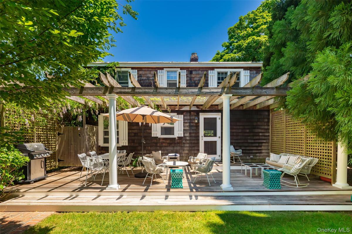 Expansive wood-finish deck with pergola structure, white columns, and a lattice privacy screen