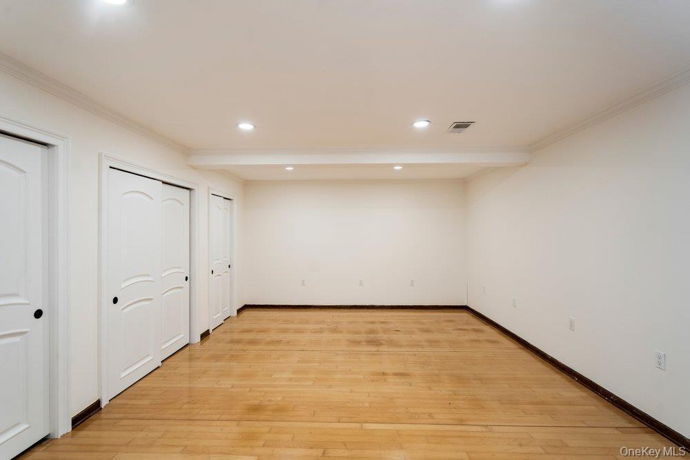 Spacious room featuring wood-finish flooring, recessed lighting, and multiple white panel doors