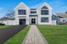 Modern Colonial exterior with board and batten style siding, black framed windows, and a covered entry that creates a strong, custom curb appeal.