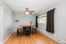 Hardwood flooring throughout featuring light gray walls, a window with natural light, and a ceiling fan with integrated lighting