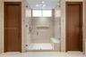 Oversized frameless glass walk-in shower with travertine tile surround, built-in bench, illuminated recessed niche, ceiling rain head, multi-function