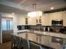 Kitchen with a sink, a chandelier, appliances with stainless steel finishes, glass insert cabinets, and decorative backsplash